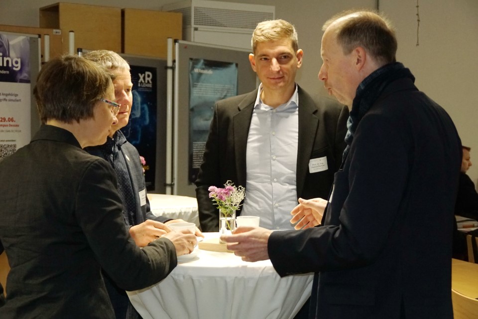 Leute im Gespräch an einem Stehtisch; Foto: Hochschule Anhalt | Renate Geue